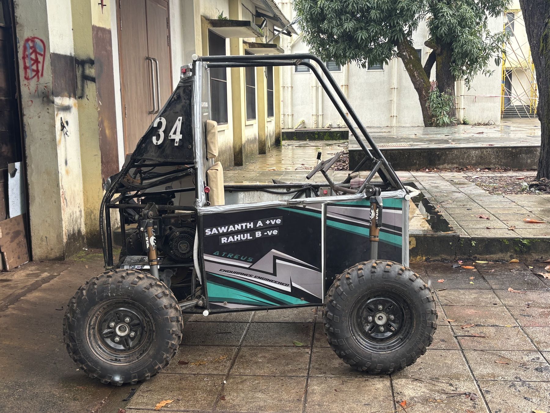 Side view of the BNR car in its black and teal livery, parked on a wet courtyard