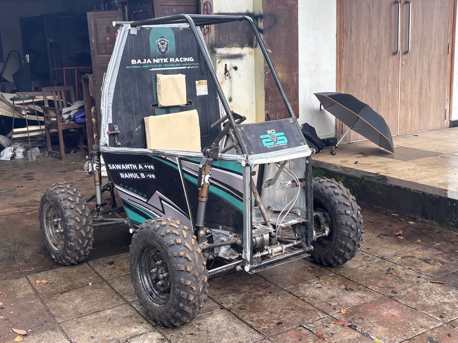 The car parked at the open doors of the team workshop