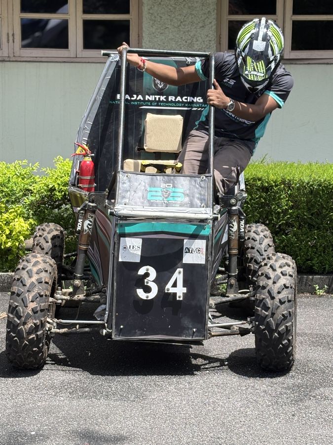 A driver in a helmet climbing into the cockpit over the side of the roll cage