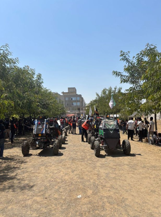 Cars lined up on a dirt track under an Endurance banner, crews around them