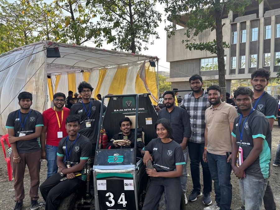 The team gathered around the car beside a tent at the competition paddock
