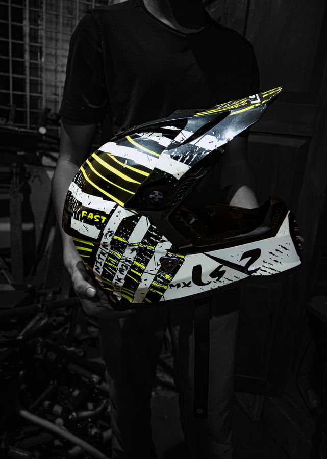 A team member holding the neon-yellow racing helmet against a dark background