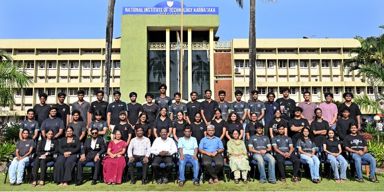 The 2026–27 BAJA NITK Racing team with faculty, posed in rows on the lawn in front of NITK’s main building