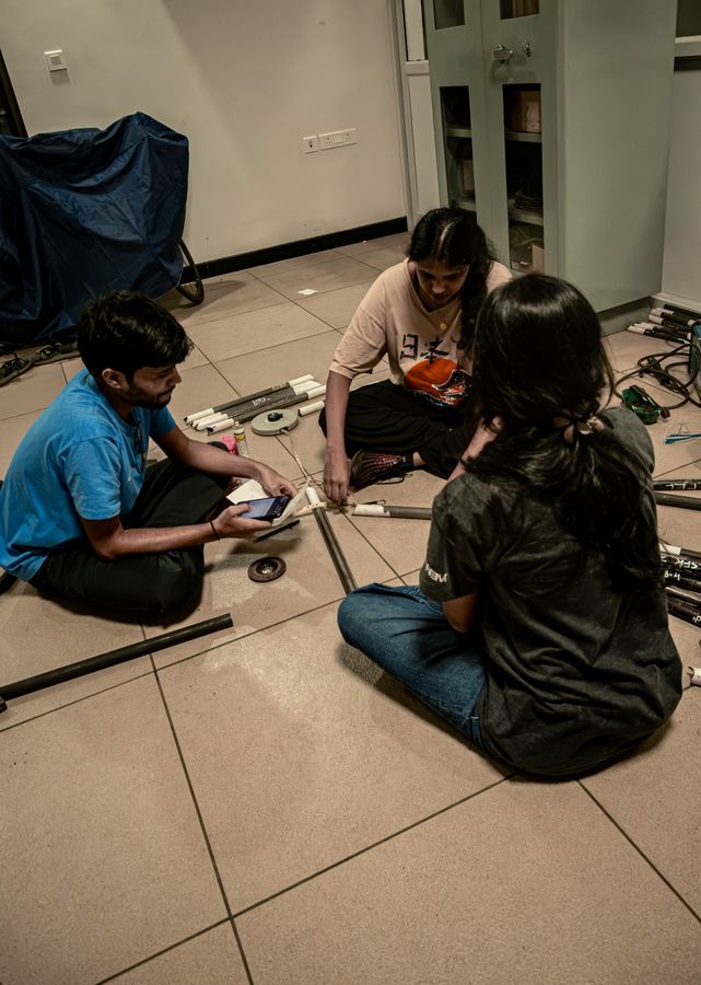 Three team members on the floor marking and measuring tubes