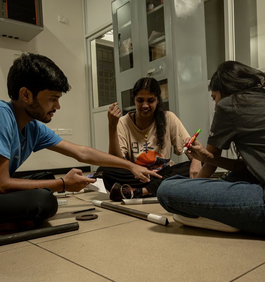 Three team members sitting on the floor discussing tube measurements