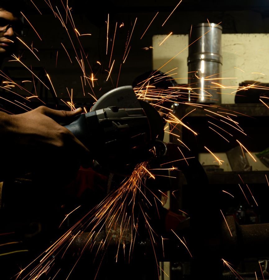 Close-up of a grinder cutting a tube, orange sparks streaking across the frame