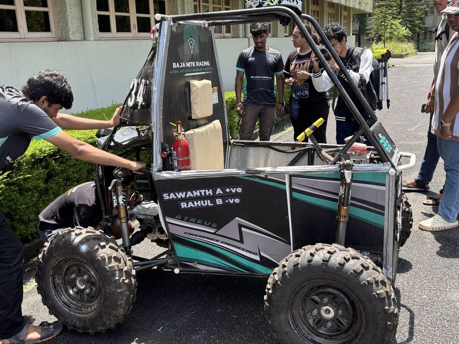 A team member leaning in to check the car while others look on