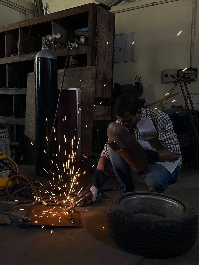 Sparks flying as a team member cuts metal next to a tyre in the workshop