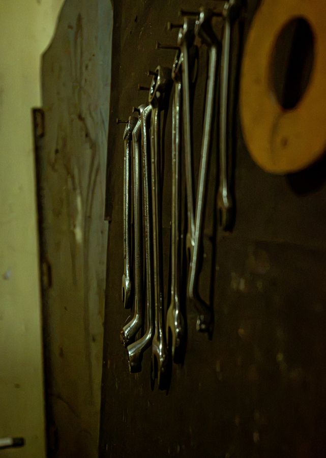 A row of spanners hanging from nails on a workshop wall